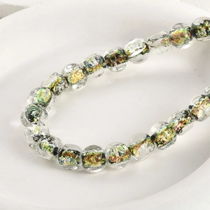 Close-up of clear glass square beads with colorful gold foil swirl for DIY jewelry making
