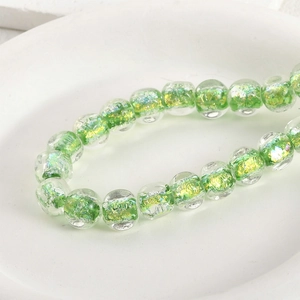 Detail of green and gold handmade glass beads with gold foil texture for DIY jewelry making