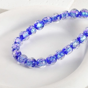 Macro view of clear blue glass beads with purple and silver glitter for DIY jewelry