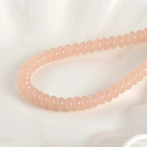 Vista macro de cuentas de vidrio rosa translúcido de 5x8mm para joyería artesanal