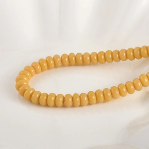 Vista macro de cuentas de vidrio amarillas en plato de cerámica para joyería DIY