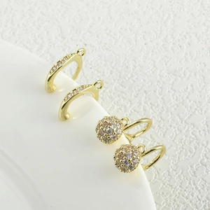 Accessori per orecchini placcati oro 14K con zirconi su un piatto di ceramica