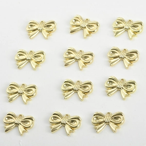 Detailed view of 12 gold plated bow charms with zircon accents for DIY jewelry making
