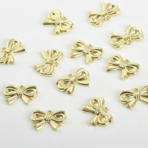 Close-up of 14k gold-plated bow heart pendants with rings for DIY jewelry making