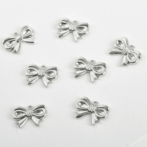 Close-up of polished silver bow-shaped charms for DIY jewelry making with hanging holes
