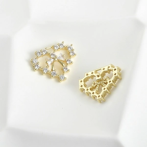 Detail view of 14k gold plated heart charm with bow design and shimmering zircon stones