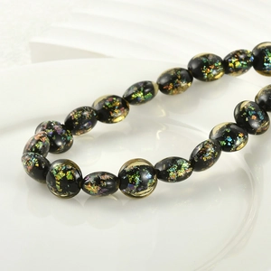 Macro detail of oval black glass beads with colorful foil inserts for DIY jewelry making