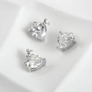 Close-up of three silver bow zircon heart pendants for DIY necklace jewelry making