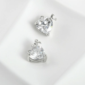 Detailed macro of two heart-shaped zircon pendants with silver bow accents and clear facets