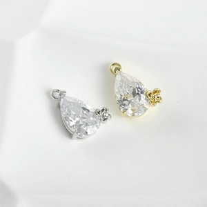 Macro shot of 14k gold-plated teardrop zircon charms with floral metal accents and rings