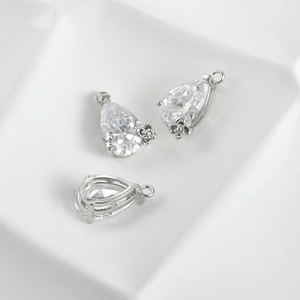 Macro shot of pear-cut zircon pendant with intricate metal flower detail and prong setting