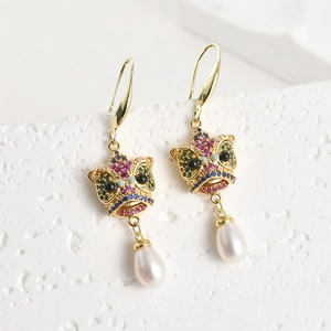Primer plano de pendientes de león chino bañados en oro de 18k con piedras y perlas
