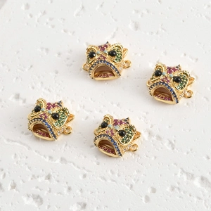 Detalle macro de los colgantes de cabeza de león bañados en oro 18k con circonitas de colores