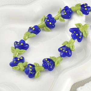Macro shot of handmade blue glass tulip beads for DIY jewelry making on white dish