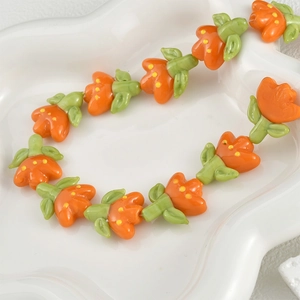 Detailed macro shot of handmade glass tulip beads in orange and green for DIY jewelry