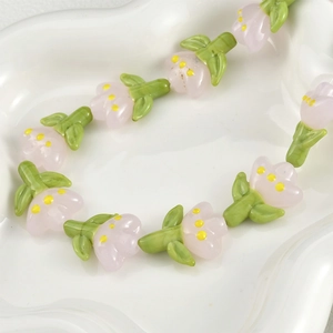 Macro detail of handmade tulip glass beads with pink petals on white tray for jewelry making