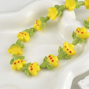 Macro view of handmade glass tulip flower beads with green base in white tray