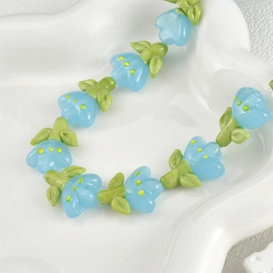 Macro shot of blue handmade glass tulip beads with green leaves for DIY jewelry making