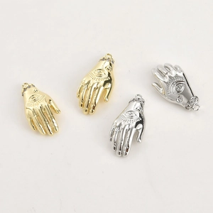 Macro detail of 14k gold and silver plated Hamsa charms with evil eye and zircon stones