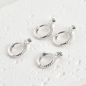 Gros plan sur des boucles d'oreilles serpent en argent avec yeux en zircon vert brillant