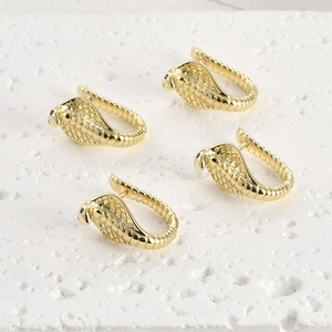 Détail macro de boucles d'oreilles cobra dorées 14k avec texture d'écailles fines