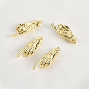 Macro view of four 14k gold-plated hand charms with pointing finger and polished finish