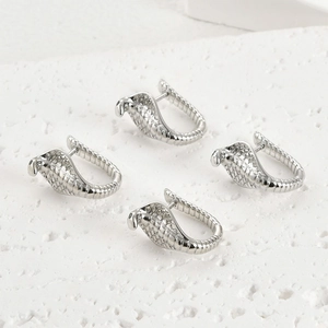 Détails macro de boucles d'oreilles serpent argentées avec texture d'écailles sur pierre