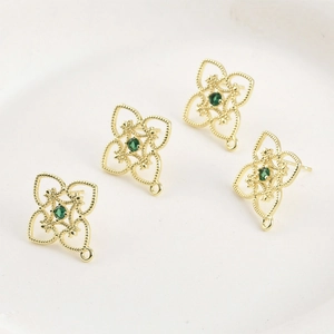 Detailed view of 14k gold-plated hollow clover studs with green stones and hanging loops