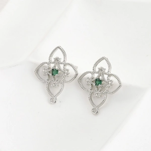 Detailed view of silver hollow floral earring components with green center gemstones