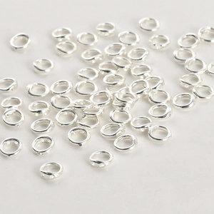 Makro-Detail von silberfarbenen Ovalperlen mit Doppellöchern für DIY-Schmuck und Bastelarbeiten