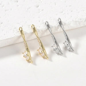 Macro shot of gold and silver S-shaped twisted pendants with sparkling zircon stones