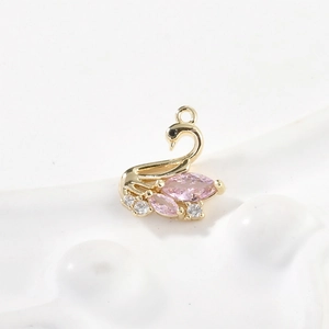 Macro detail of 14k gold plated swan pendant with pink zircon and white crystal gems