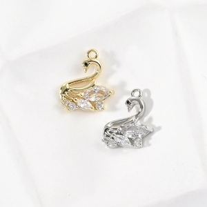 Close-up of 14k gold-plated swan charms with sparkling clear zircon stones