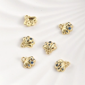 Macro detail of 14k gold plated seashell pendants with sparkling blue zircon stones