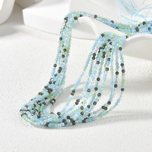 Detailed view of 2mm faceted glass beads in light blue, green and dark grey layers