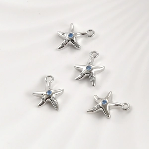 Close-up of four starfish pendants with blue zircons and shiny silver plating
