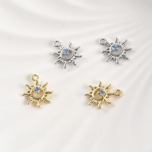 Close-up of gold and silver sun pendants featuring blue zircon in center for jewelry