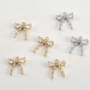 Detailed close-up of bow-shaped jewelry pendants with cubic zirconia in gold and silver