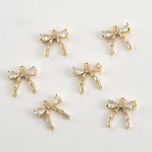 Macro detail of 14k gold plated bow charms with clear cubic zirconia for DIY jewelry