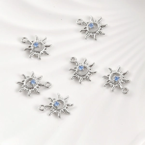 Macro view of six sun-shaped 14k gold plated charms with blue zircon center stones