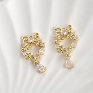 Detailaufnahme von 14k vergoldeten Kranzohrringen mit rosa Zirkon-Herz und Schmetterling