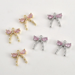 Detailed view of 14k gold plated bow pendants with pink pear-shaped zircon stones