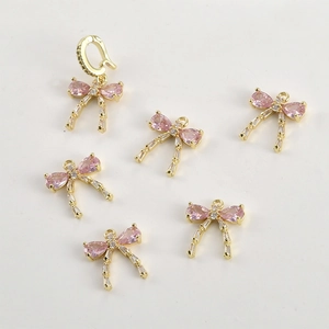 Close-up of pink pear-cut stone bow pendants with 14k gold plated settings for DIY jewelry