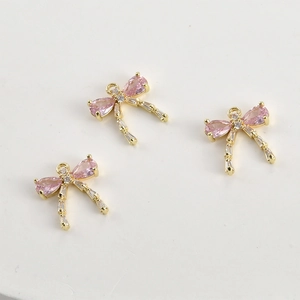 Detail of three 14k gold plated bow pendants with pink and clear zircon crystals