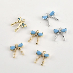 Detail of 14k gold plated bow pendants with blue stones and cubic zirconia inlay