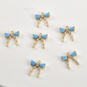 Close-up of six gold-plated bow pendants with blue zircons for DIY jewelry making