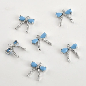 Detailed view of silver bow-knot charms with blue teardrop zircon for DIY jewelry making