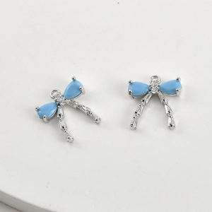 Macro detail of two light blue zircon bow pendants with silver plating for DIY jewelry