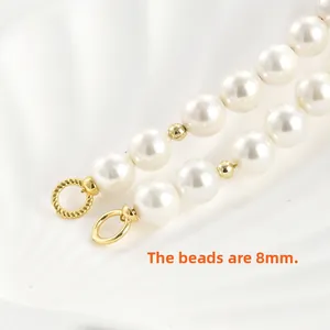 Vista macro detallada de perlas de 8mm con anillos de conexión trenzados en oro de 14k