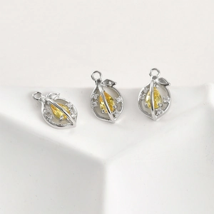 Detailed view of three hollow leaf pendants with yellow pear-cut stones and tiny zircon